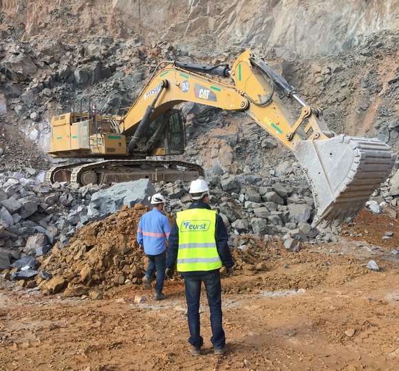 Equipe técnica acompanhando escavadeira em operação em pedreira